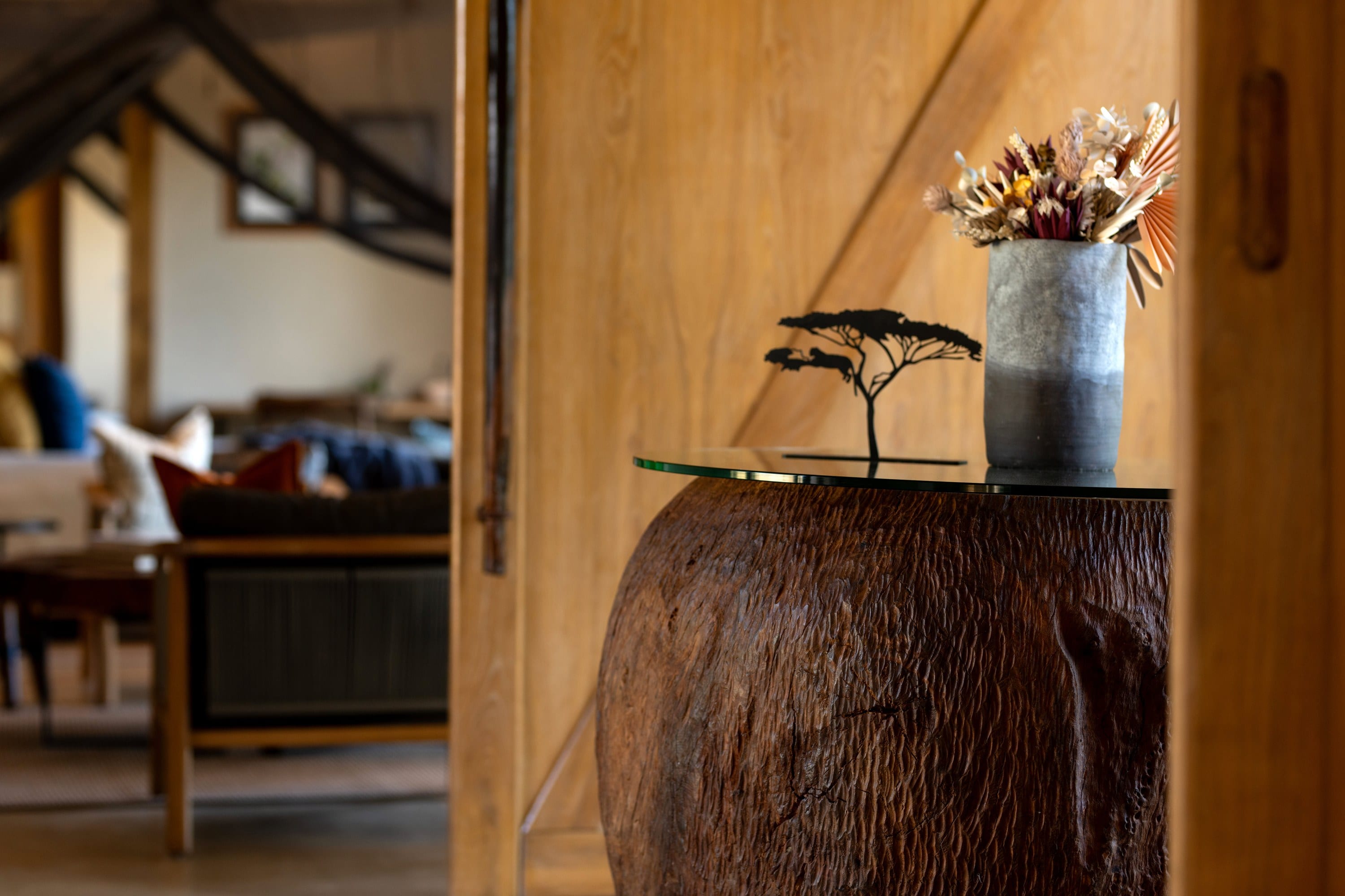 A timber deck and pool under a thatched roof, opening onto acacia savanna.