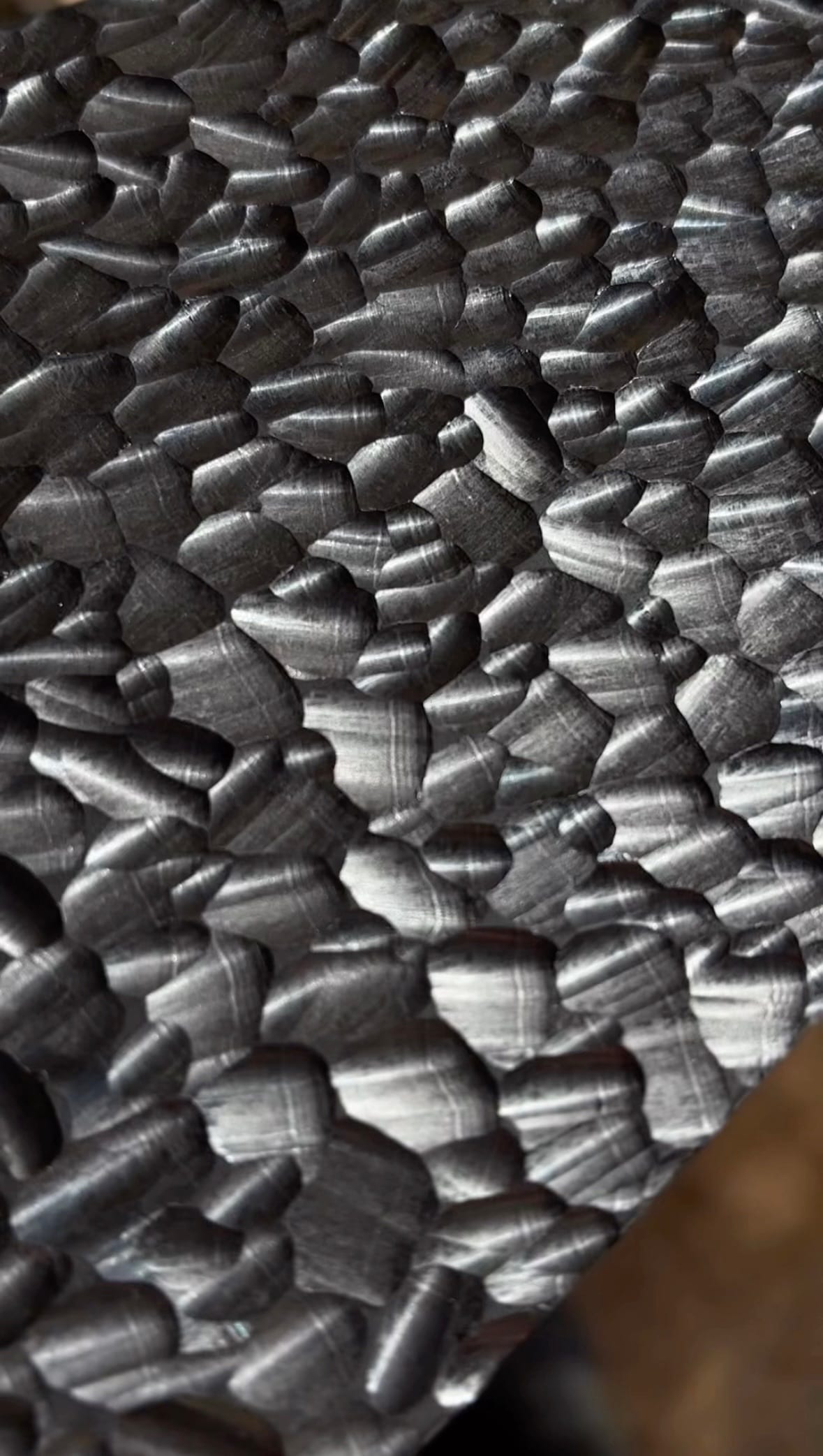 A close-up of blackened hand-carved scalloped timber.