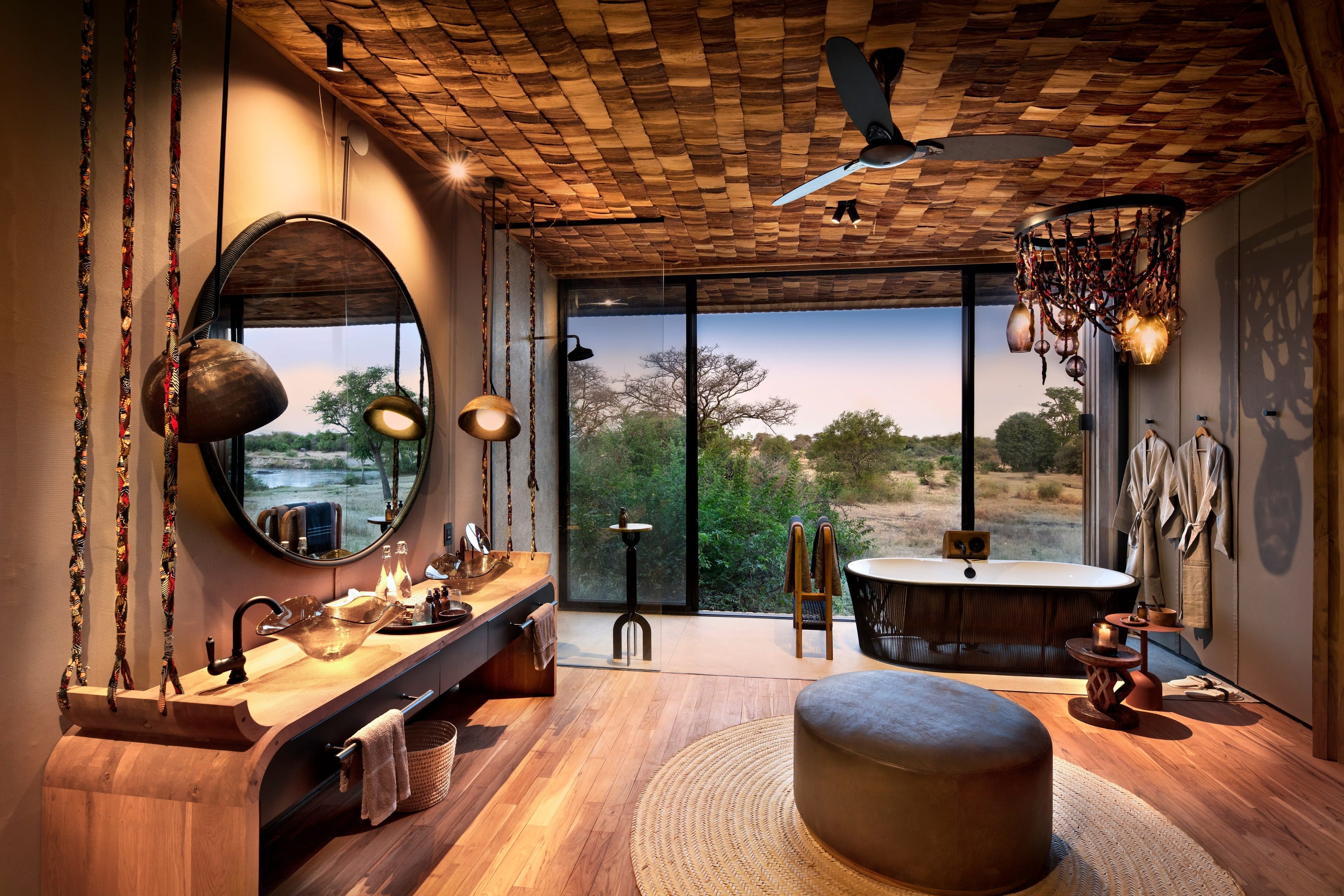 A lodge bathroom with a freestanding bath, twin timber vanities, and a view to the trees.