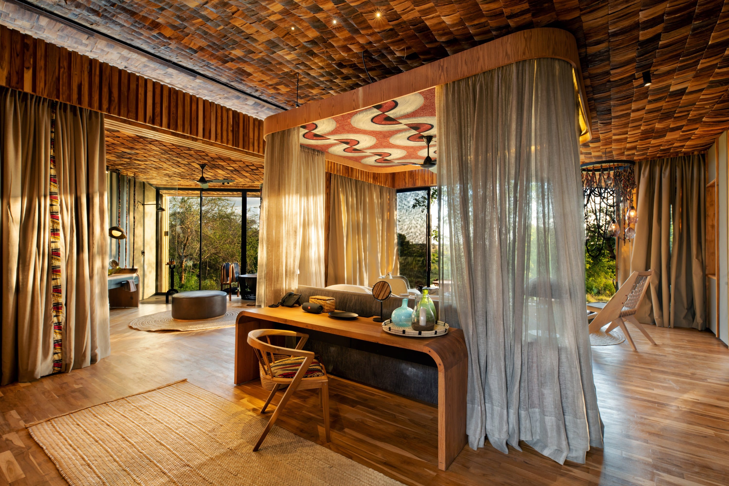 A lodge suite with a timber daybed at the window and a view across the bush.