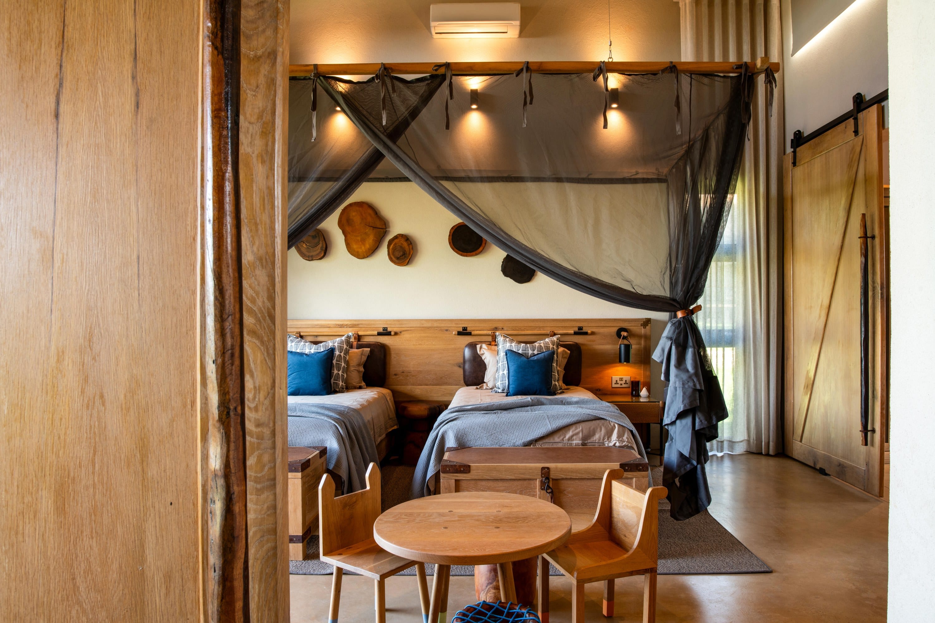 A living room under thatch with a stone fireplace, a leather sofa, and a view to the river.