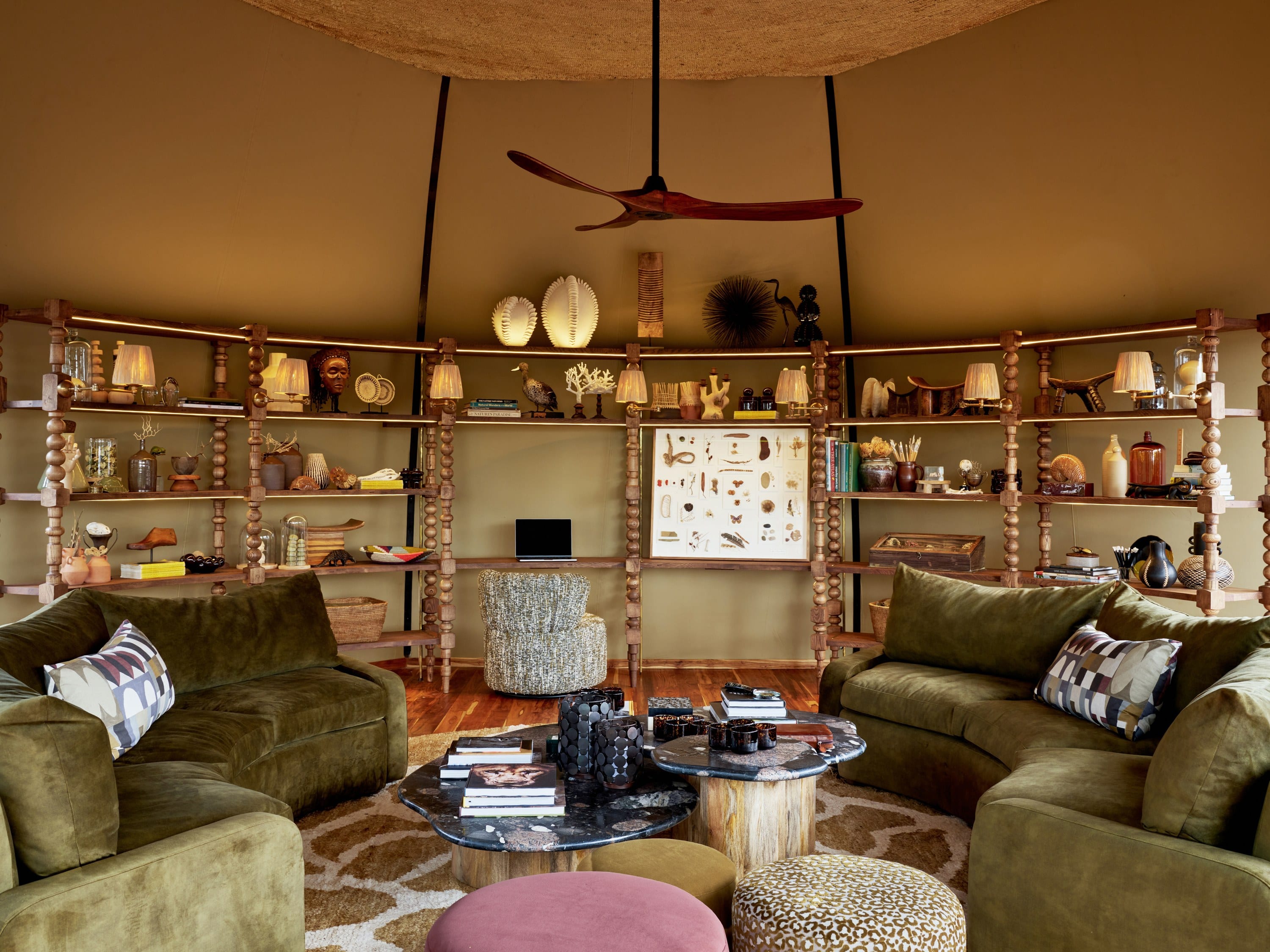 A dining room with a long timber table, upholstered chairs, and a thatched roof.
