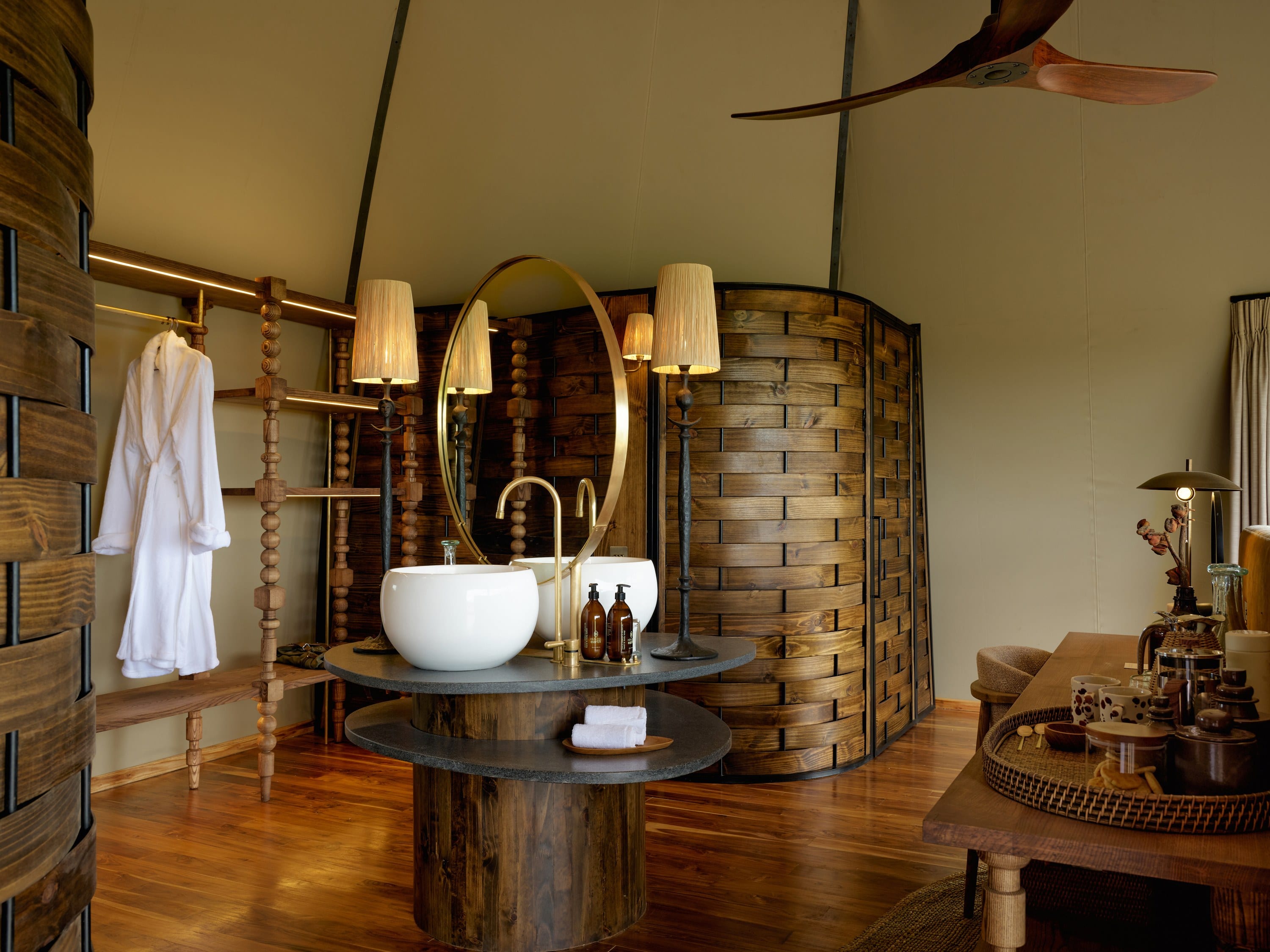 A lounge with a stone fireplace, leather seating, and a view to the bush.